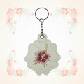Cream and red hibiscus keychain on a pale tropical background