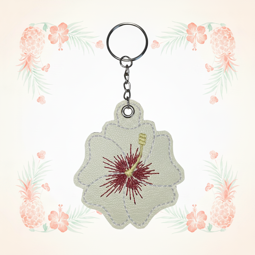 Cream and red hibiscus keychain on a pale tropical background