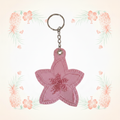 Pink plumeria keychain with full chain on a pale tropical background without a shadow