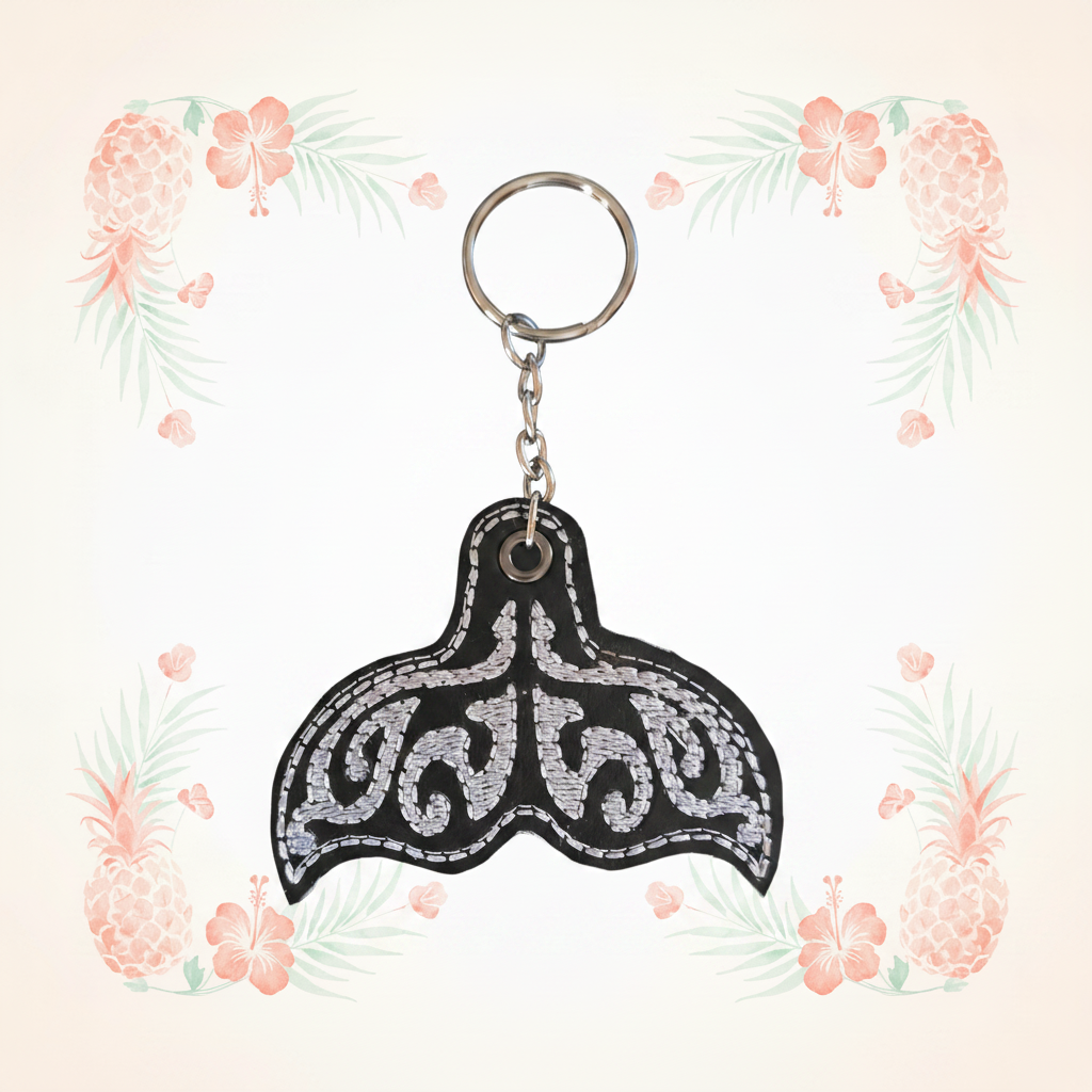 Whale tail embroidered keychain on a pale tropical background without a shadow